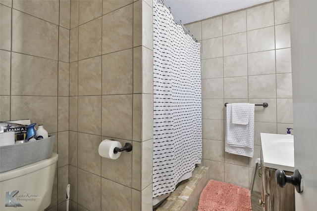 bathroom featuring toilet, vanity, a textured ceiling, and walk in shower