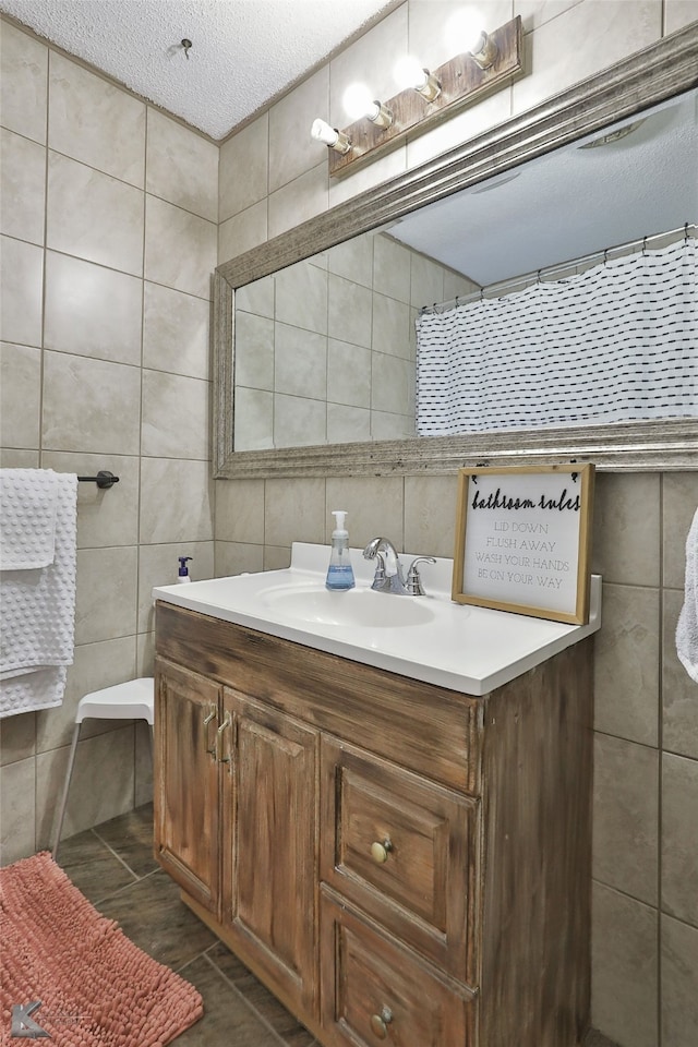 bathroom with vanity, tile patterned floors, a shower with shower curtain, a textured ceiling, and tile walls