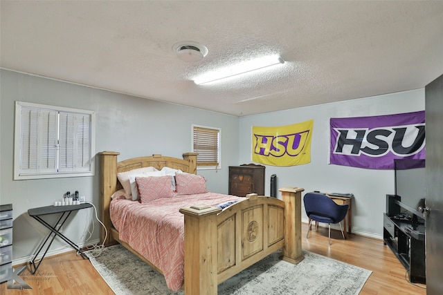 bedroom featuring a textured ceiling and light hardwood / wood-style flooring