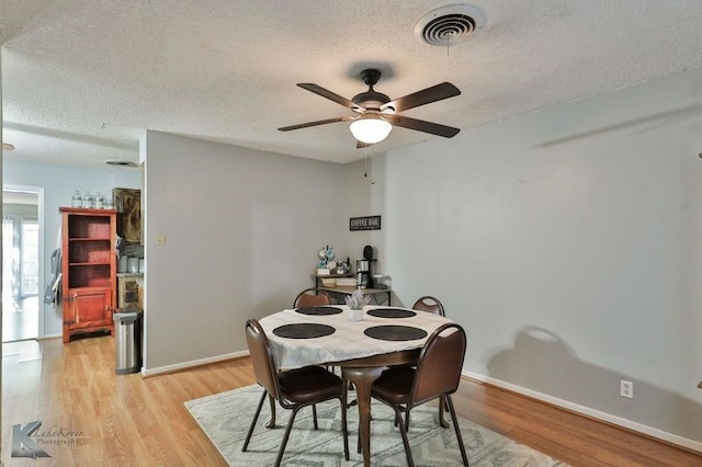 dining space featuring ceiling fan, light wood-type flooring, and a textured ceiling