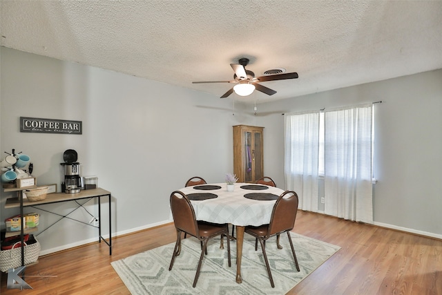 dining room with ceiling fan, a textured ceiling, and light wood-type flooring