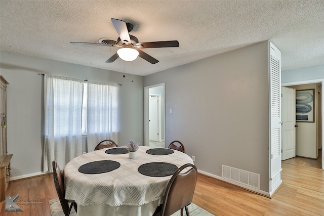 dining area with ceiling fan, light hardwood / wood-style floors, and a textured ceiling