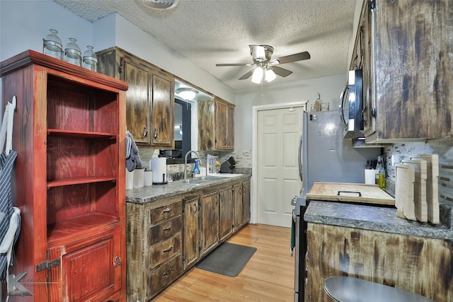 kitchen featuring a textured ceiling, backsplash, light hardwood / wood-style flooring, and sink