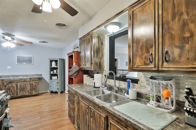 kitchen with a textured ceiling, light wood-type flooring, sink, and tasteful backsplash