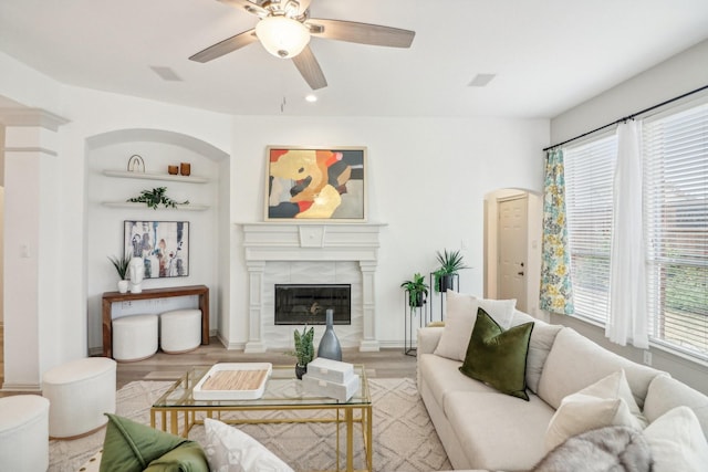 living room with ceiling fan, light wood finished floors, and a fireplace