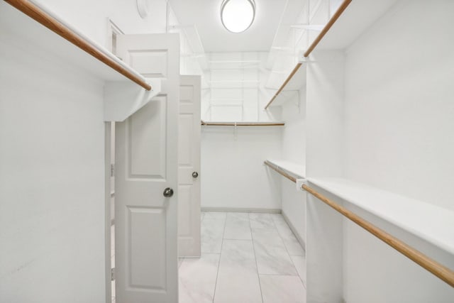 walk in closet featuring marble finish floor