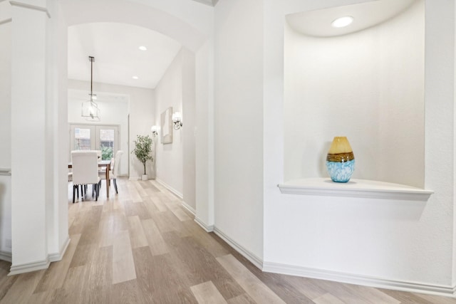 corridor featuring arched walkways, recessed lighting, baseboards, and wood finished floors