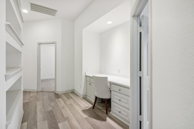 unfurnished office with baseboards, visible vents, light wood-style flooring, built in desk, and recessed lighting