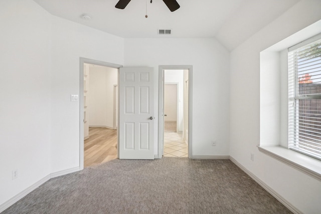 interior space with carpet, visible vents, vaulted ceiling, and baseboards