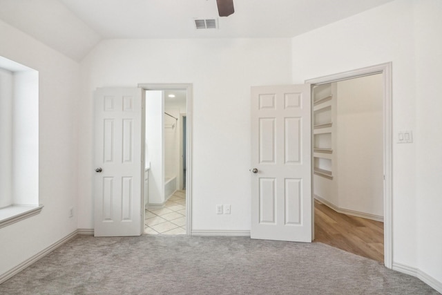 unfurnished bedroom featuring connected bathroom, visible vents, vaulted ceiling, and carpet flooring