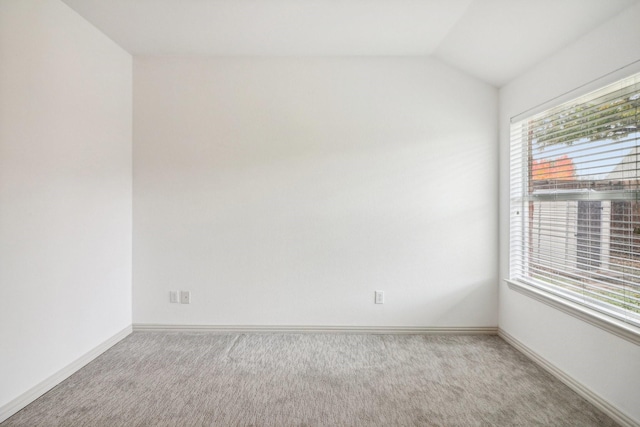 empty room with carpet floors, baseboards, and vaulted ceiling