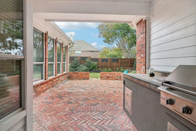 view of patio / terrace with grilling area, an outdoor kitchen, and fence