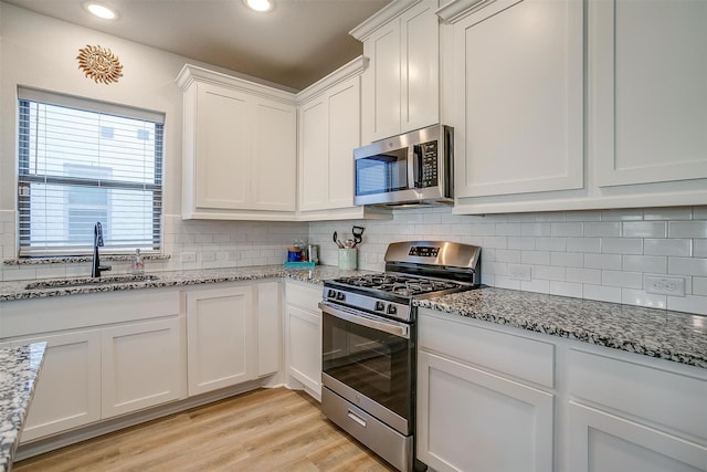 kitchen featuring stainless steel appliances, sink, white cabinets, and decorative backsplash