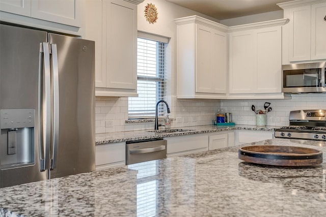 kitchen with light stone counters, white cabinetry, decorative backsplash, and appliances with stainless steel finishes