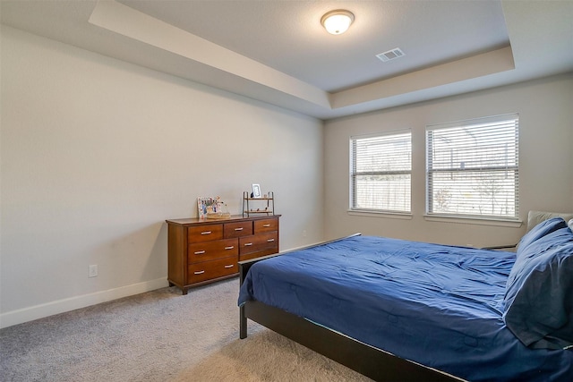 bedroom with light carpet and a tray ceiling