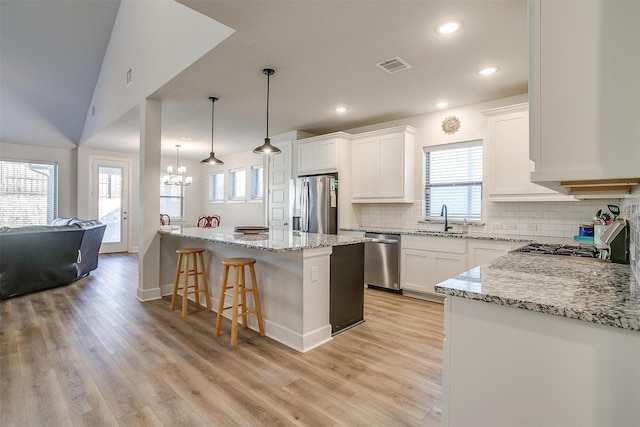 kitchen featuring sink, white cabinetry, a center island, appliances with stainless steel finishes, and pendant lighting