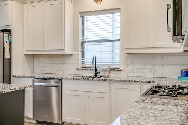 kitchen featuring light stone counters, sink, and white cabinets