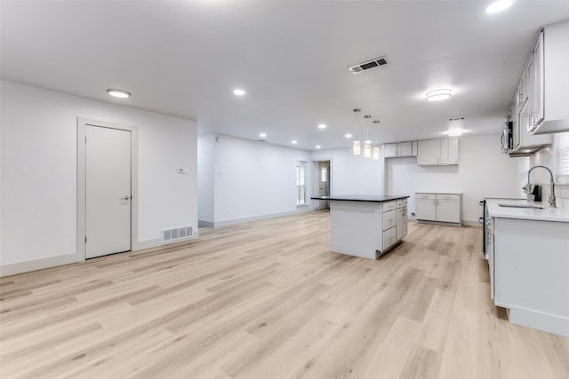 kitchen featuring decorative light fixtures, a kitchen island, light hardwood / wood-style floors, and sink