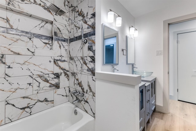 bathroom with hardwood / wood-style floors, vanity, and tiled shower / bath combo