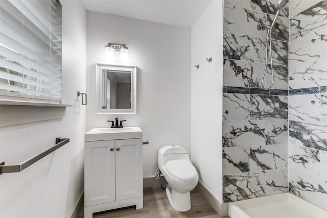 bathroom with a tile shower, vanity, hardwood / wood-style flooring, and toilet