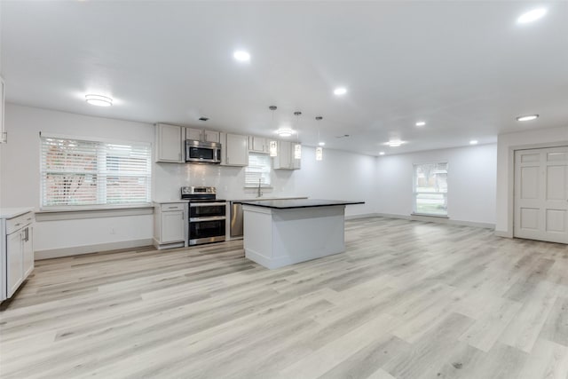 kitchen with a healthy amount of sunlight, pendant lighting, stainless steel appliances, and light hardwood / wood-style flooring