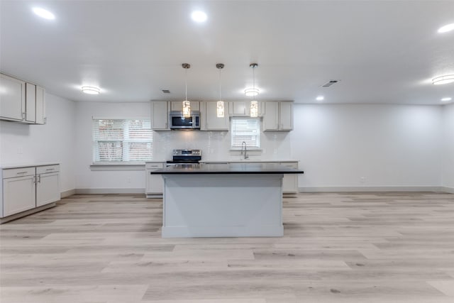 kitchen featuring appliances with stainless steel finishes, light wood-type flooring, decorative light fixtures, and gray cabinetry