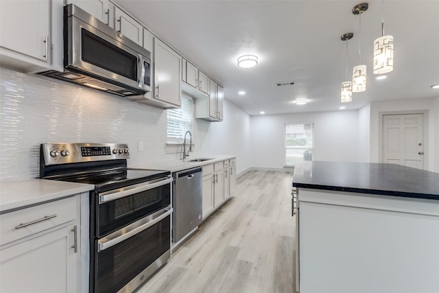 kitchen with sink, white cabinets, stainless steel appliances, and light hardwood / wood-style flooring