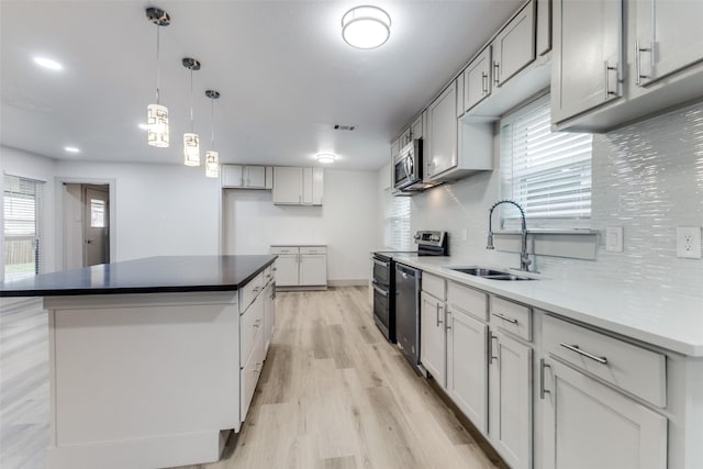 kitchen featuring appliances with stainless steel finishes, light wood-type flooring, a wealth of natural light, and sink