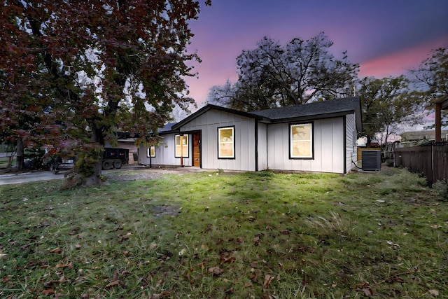 view of front of home with central AC unit and a lawn