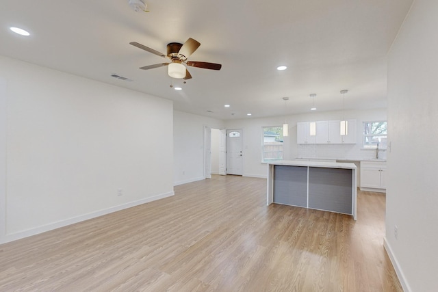 unfurnished living room with ceiling fan, sink, and light hardwood / wood-style flooring