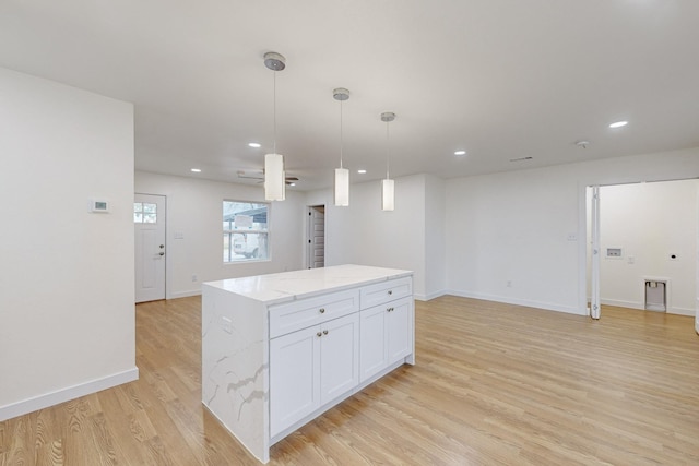 kitchen with light stone countertops, decorative light fixtures, a center island, light hardwood / wood-style floors, and white cabinetry