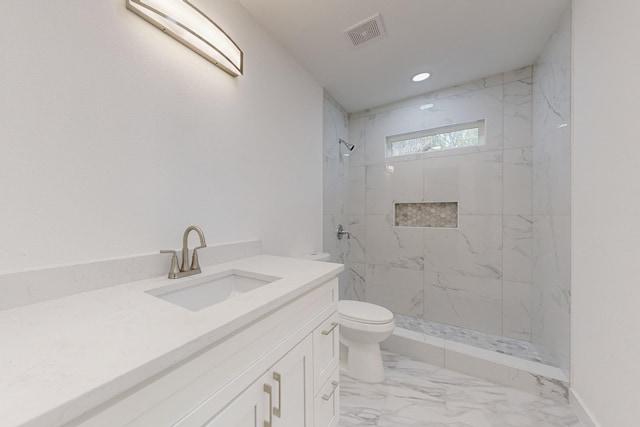 bathroom featuring toilet, vanity, and tiled shower