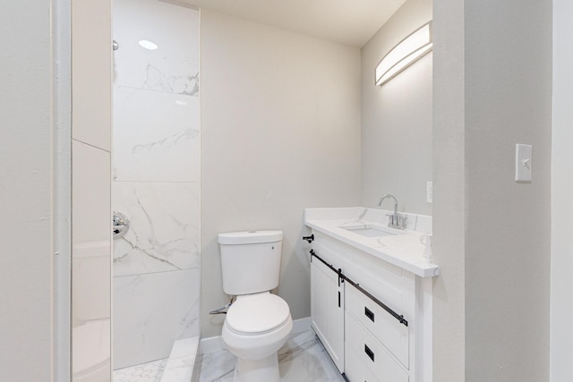 bathroom with vanity, toilet, and tiled shower