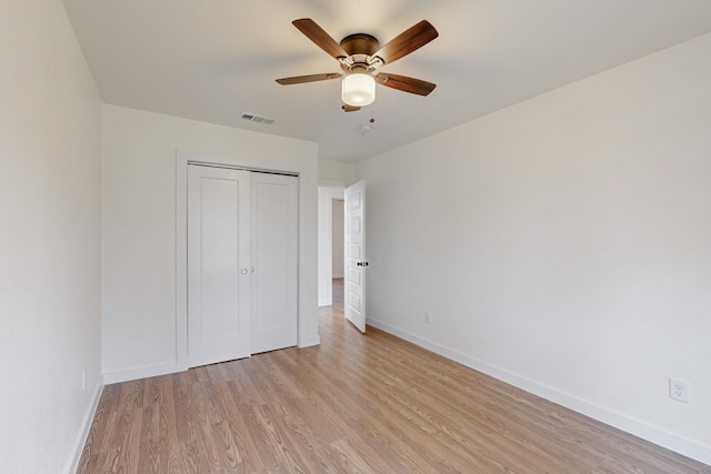 unfurnished bedroom featuring a closet, light hardwood / wood-style floors, and ceiling fan