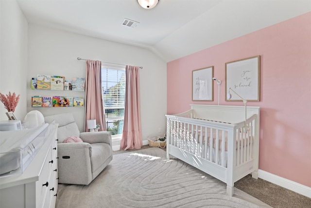 carpeted bedroom with lofted ceiling and a crib