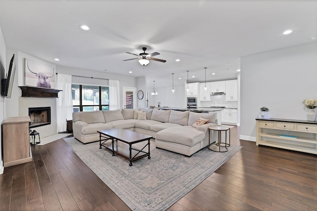 living room featuring ceiling fan and dark hardwood / wood-style floors