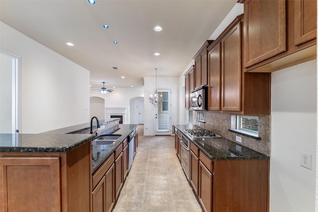 kitchen featuring backsplash, dark stone counters, light tile patterned floors, stainless steel appliances, and a chandelier