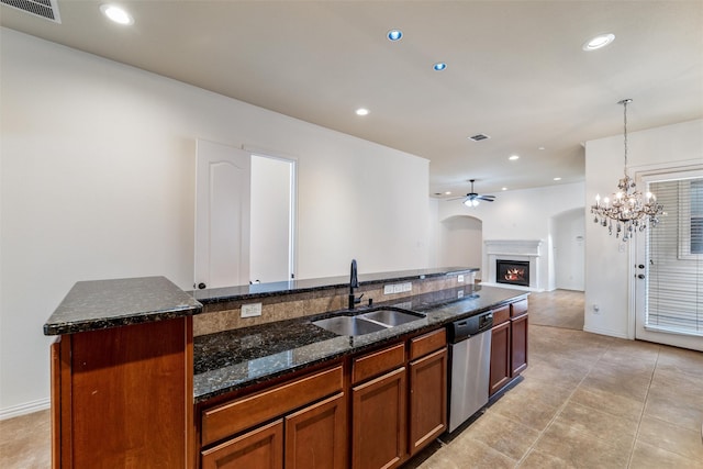 kitchen with sink, stainless steel appliances, dark stone countertops, light tile patterned floors, and ceiling fan with notable chandelier