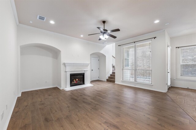 unfurnished living room with ceiling fan with notable chandelier, light wood-type flooring, and crown molding