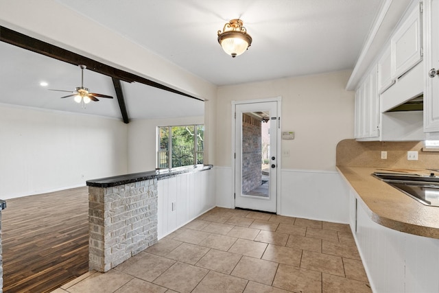 kitchen featuring kitchen peninsula, light wood-type flooring, ceiling fan, vaulted ceiling with beams, and white cabinetry