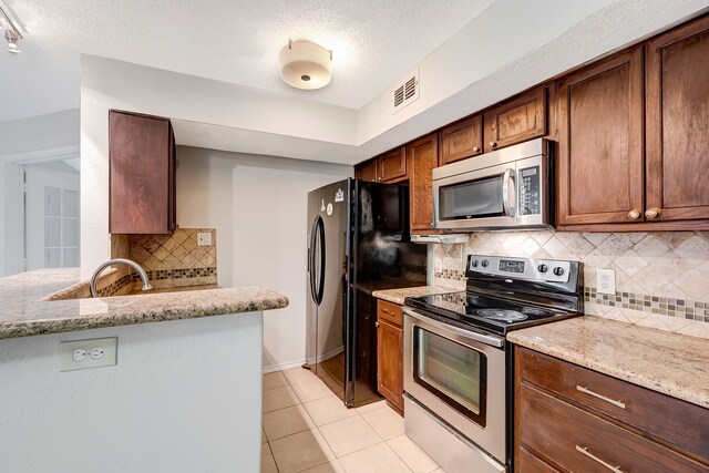 kitchen featuring light stone countertops, appliances with stainless steel finishes, and decorative backsplash