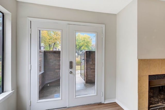 entryway featuring a tiled fireplace, light hardwood / wood-style flooring, and french doors