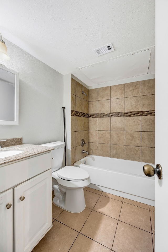 full bathroom featuring tile patterned flooring, tiled shower / bath combo, vanity, a textured ceiling, and toilet