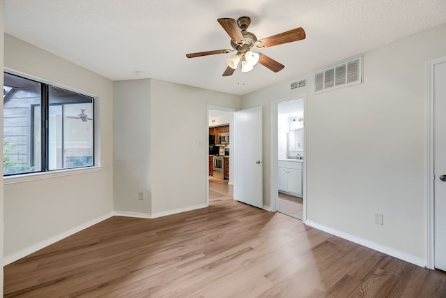 spare room with ceiling fan, a textured ceiling, and light wood-type flooring