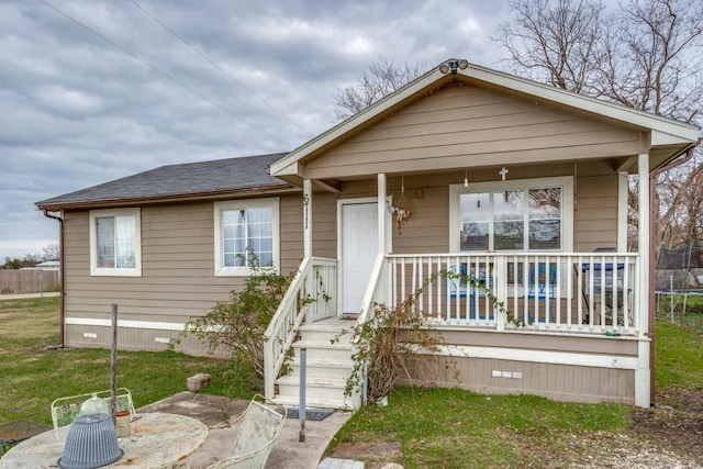 view of front of house featuring covered porch, a trampoline, and a front yard