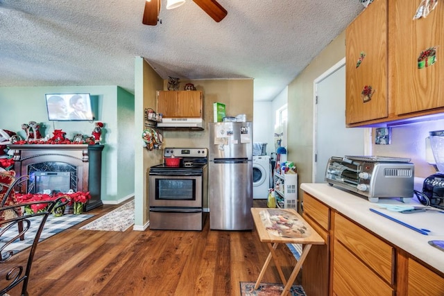 kitchen featuring ceiling fan, a textured ceiling, dark hardwood / wood-style flooring, washer / dryer, and stainless steel appliances