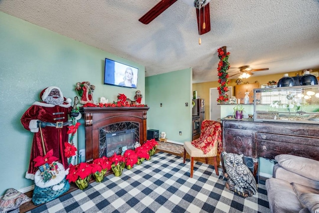 living room featuring a fireplace, ceiling fan, and a textured ceiling