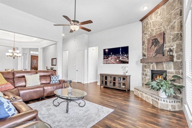 living room with a stone fireplace, dark hardwood / wood-style flooring, and ceiling fan with notable chandelier