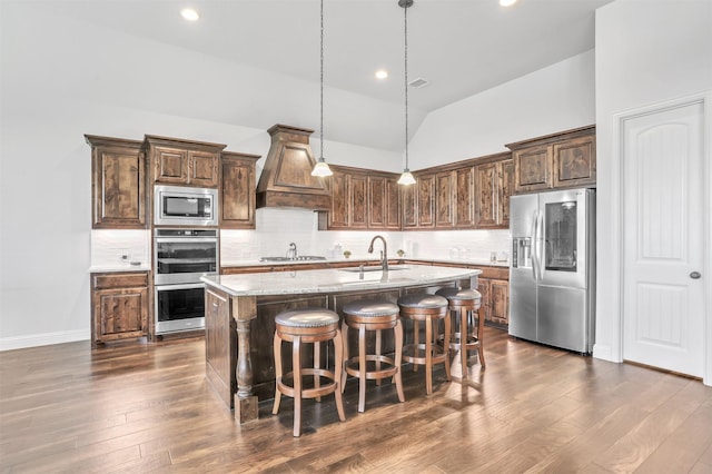 kitchen featuring stainless steel appliances, high vaulted ceiling, dark hardwood / wood-style floors, premium range hood, and a center island with sink