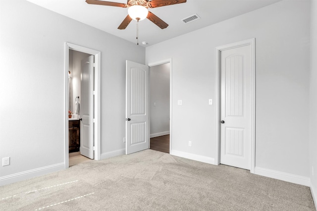 unfurnished bedroom with light colored carpet, ensuite bath, and ceiling fan